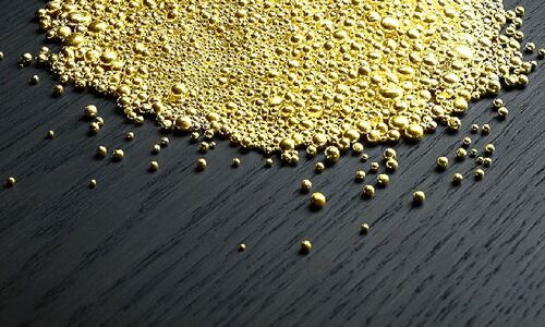 Goldgranulat präsentiert auf einer schwarzen Oberfläche
